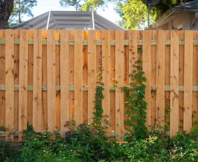A wooden picket fence surrounds a green lawn, providing privacy and protection for a backyard.