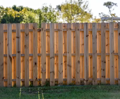 Wooden picket fence surrounding a green lawn, highlighting the importance of fence maintenance for privacy.