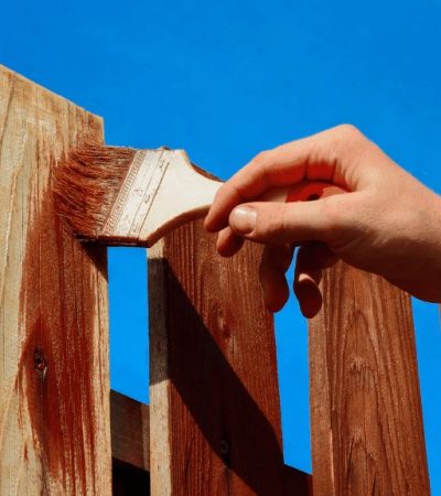 A person is staining a fence