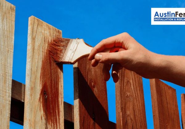 A person is staining a fence