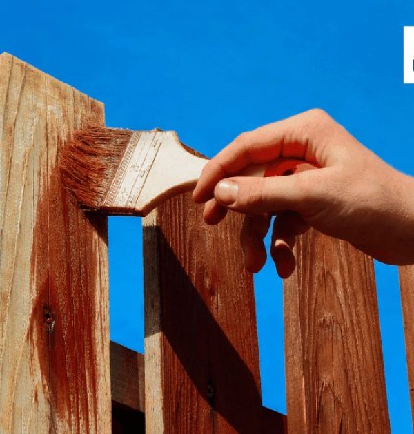 A person is staining a fence