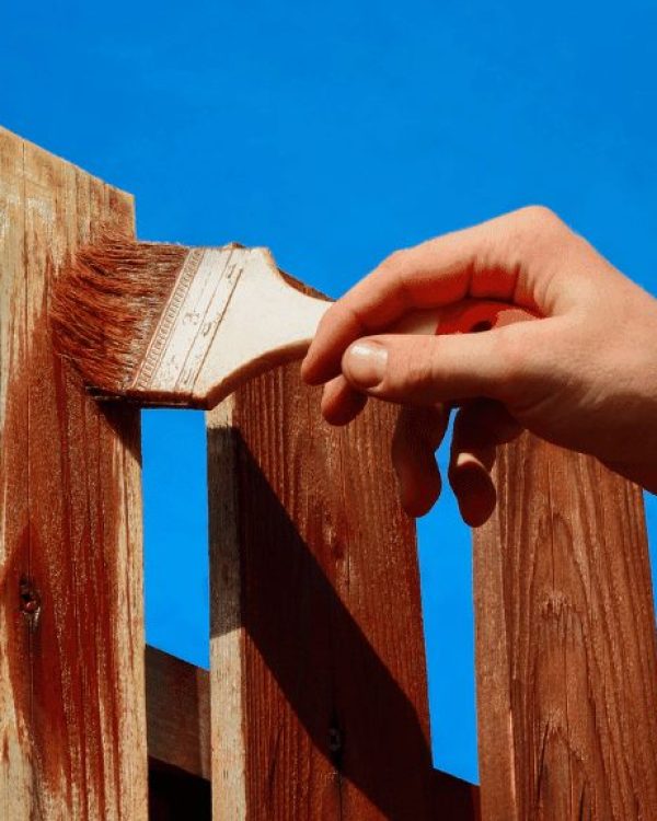 A person is staining a fence